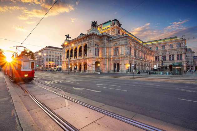 Die Wiener Staatsoper, vor der Oper fährt eine rote Straßenbahn.