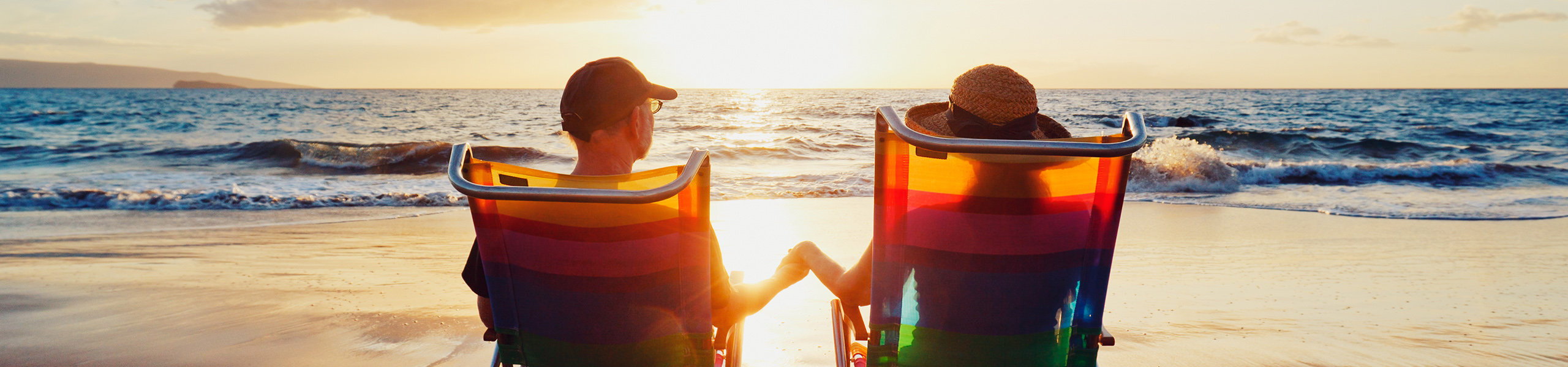 Ein Paar am Strand in Liegestühlen die den Sonnenuntergang anschauen
