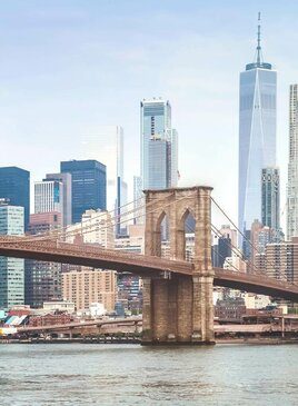 Viele Wolkenkratzer hinter der Brooklyn Brücke aus Stein und Metal.