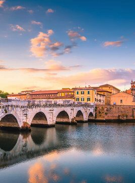 Die steinerne Tiberius Brücke steht über dem Fluss Marecchia beim Sonnenuntergang