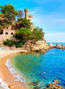 Ein Strand und Meer im Vorderung. Im Hintergrund ist eine Festung.