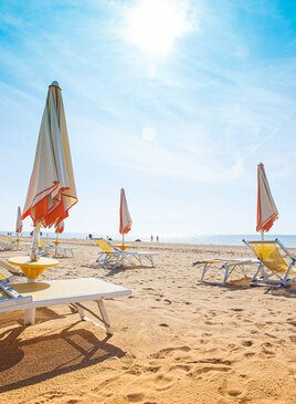 Ein Sandstrand mit Liegestühlen und Sonnenschirmen
