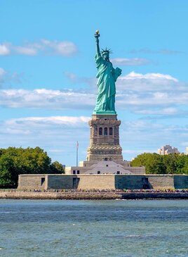 Die Freiheitsstatue in New York. Es ist eine türkise Statue einer Frau die ein Buch und eine Fackel hält.
