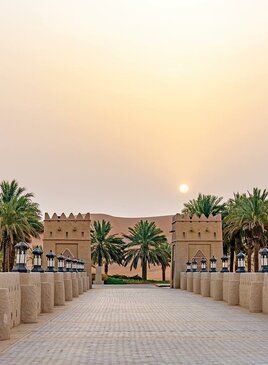 Eine Steinbrücke an deren Ende zwei kleine Türme stehen. Hinter den Türmen sind Palmen.