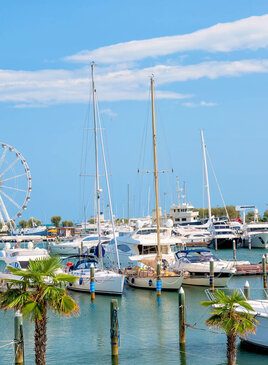 Eine Anlegestelle mit vielen Booten. Im Hintergrund ist ein Riesenrad.