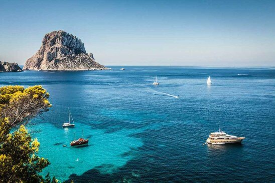 Cala d'Hort, Ibiza (Spain) Ein blaues Meer. Aus dem Meer ragen Felsen hervor.
