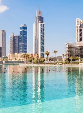 Ein Blick über das Wasser auf Wolkenkratzer mit Palmen.
