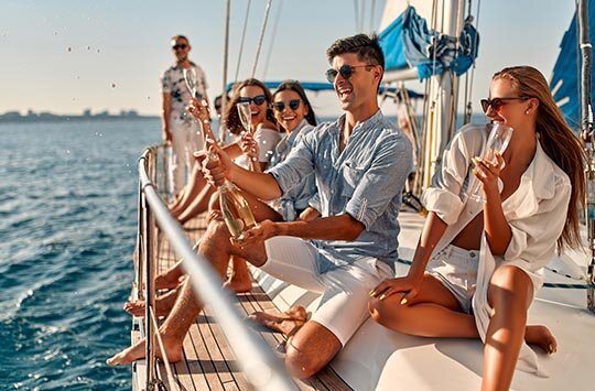 Junge Leute genießen einen Champagner auf einer Yacht.