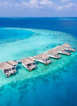 Bungalows stehen über dem Wasser in einer Reihe.